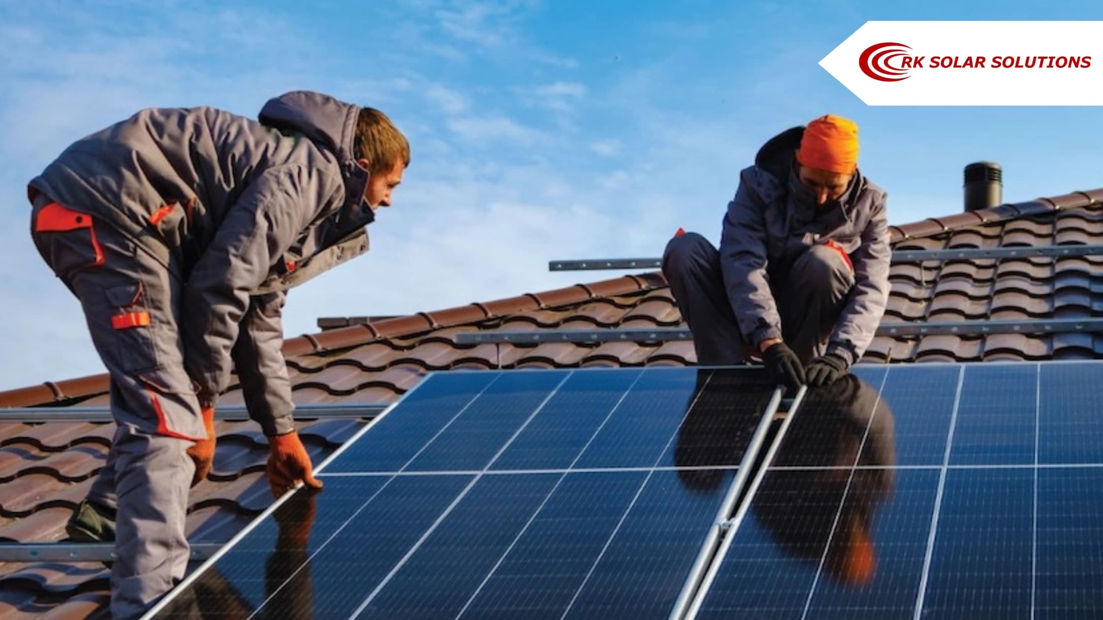 Two installers fixing solar panels onto a tiled roof