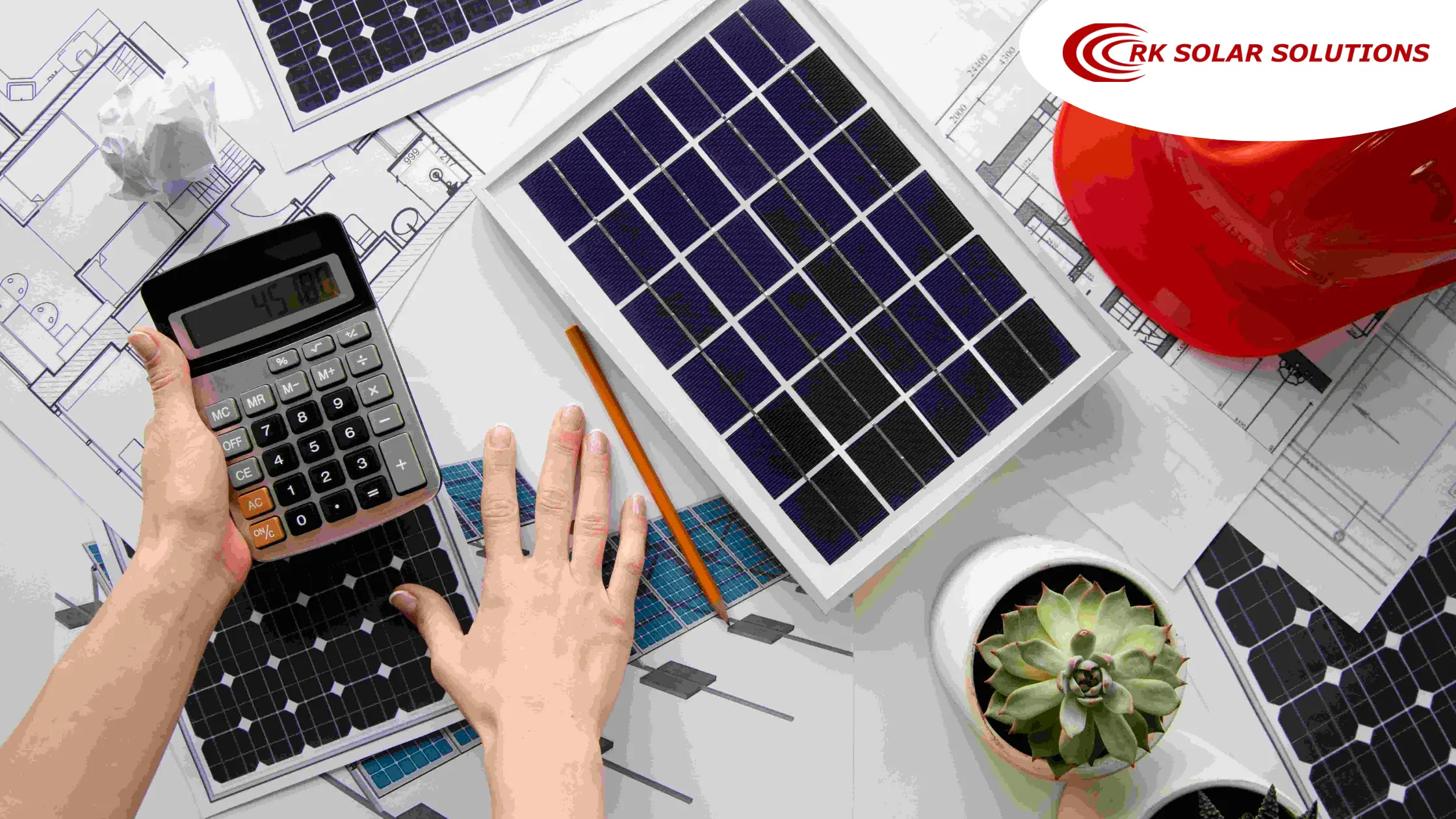 Hands using a calculator beside small solar panels laid on building plans