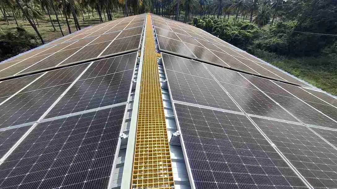 Large solar array on an industrial shed roof with a yellow maintenance walkway