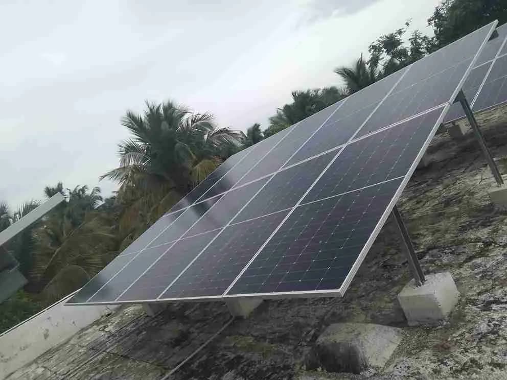 Elevated solar array on a house terrace with coconut palms behind