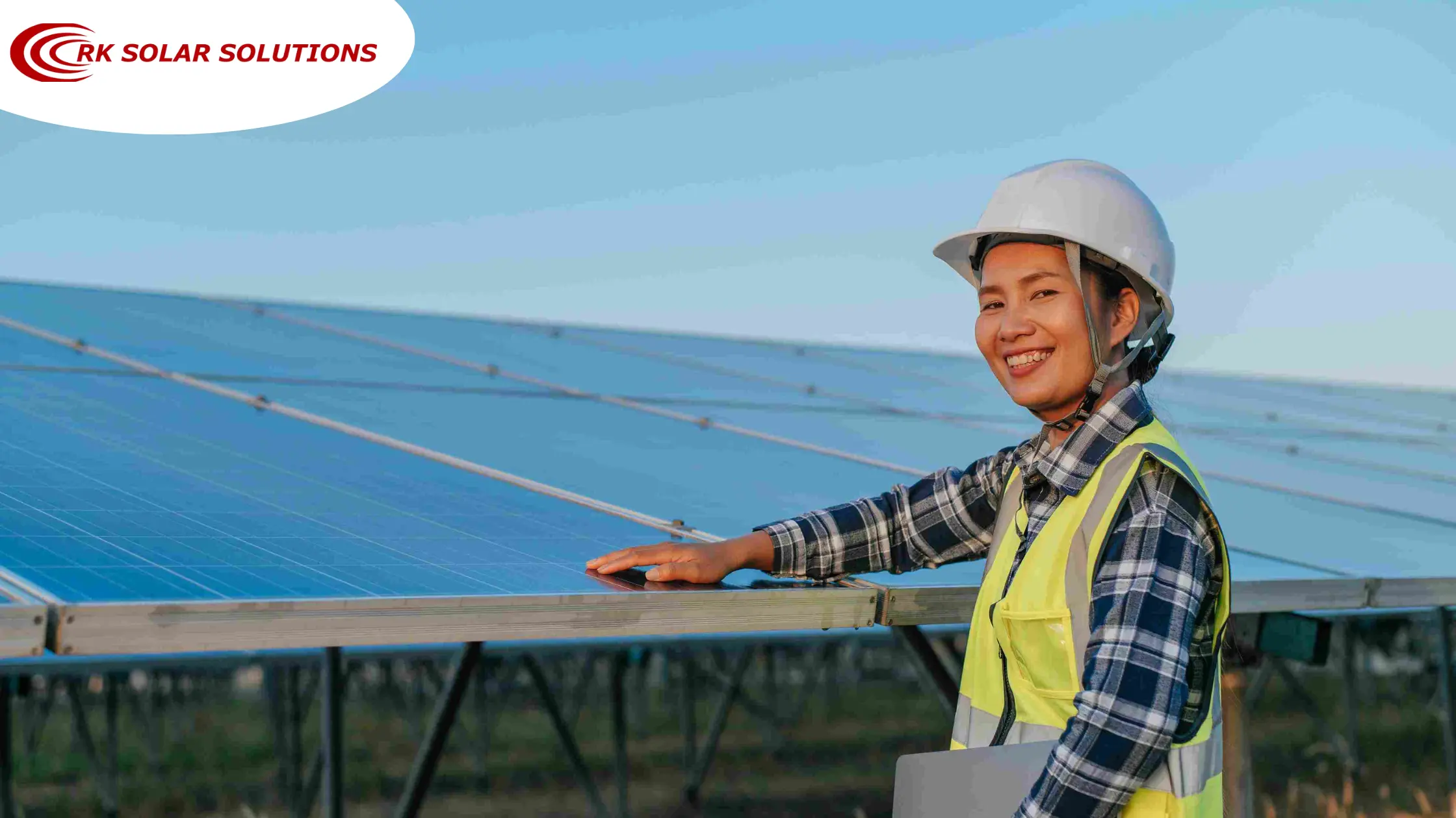 Engineer in a hard hat standing beside a row of solar panels