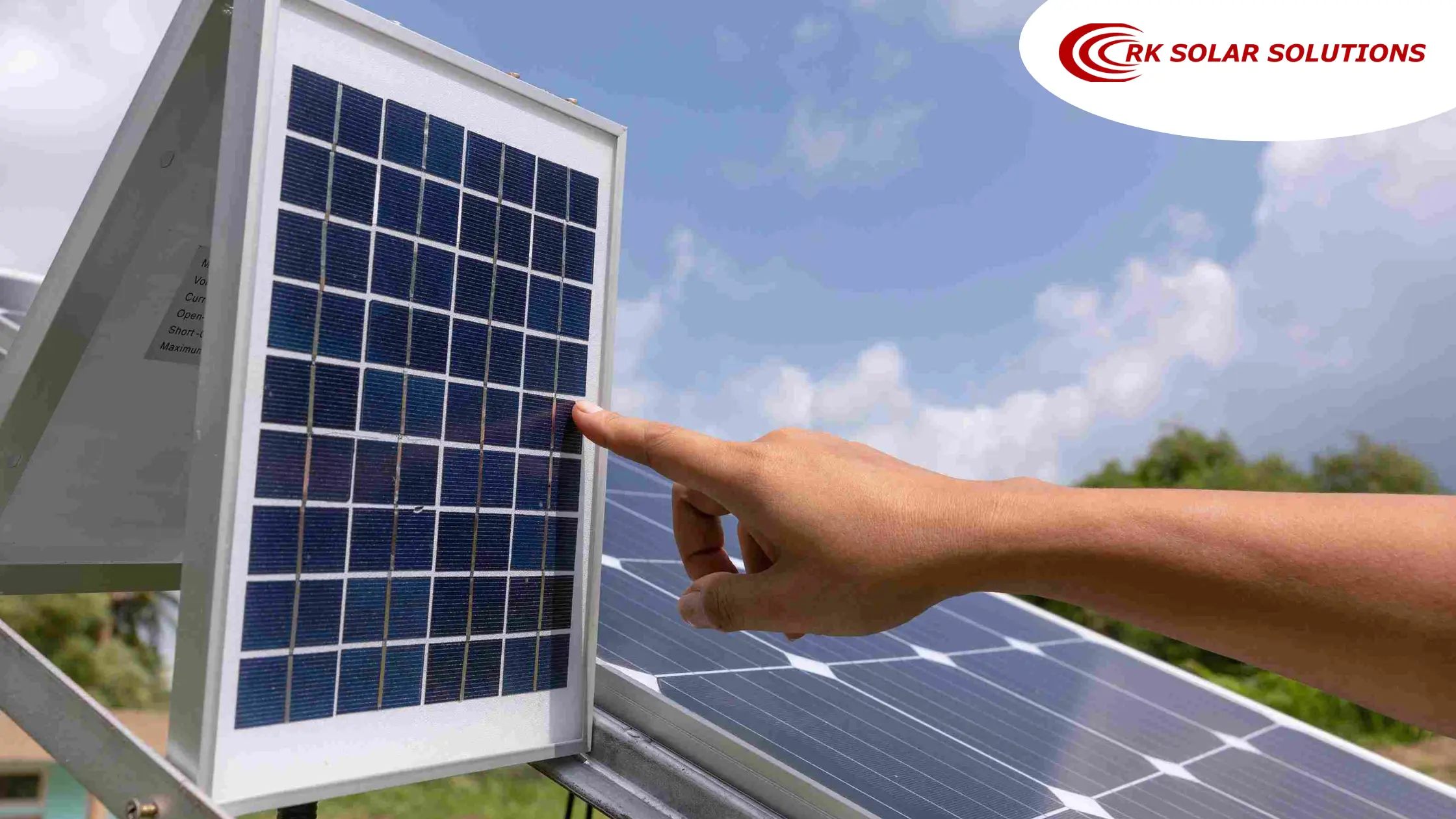 Hand pointing at a small solar panel outdoors